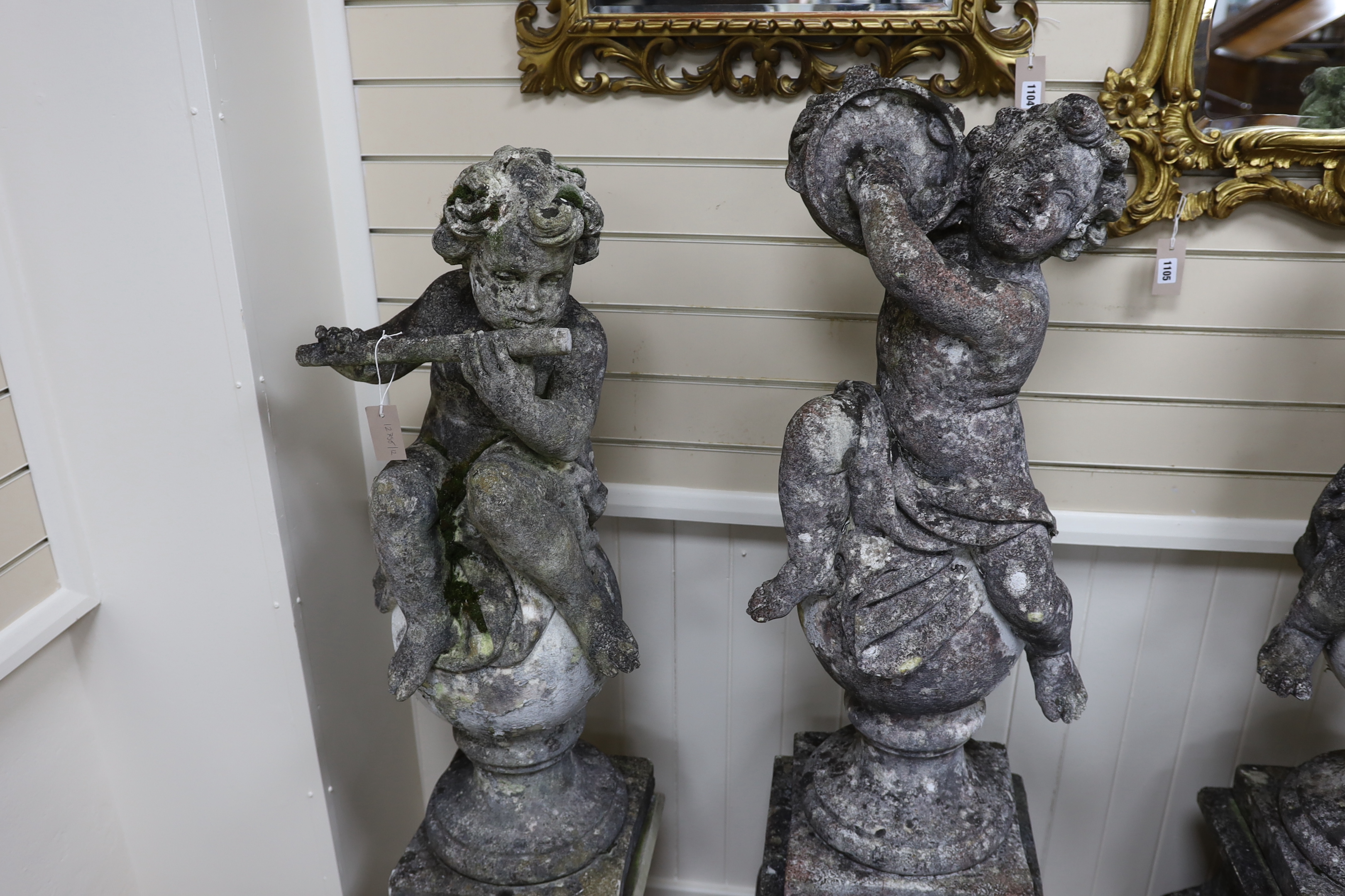 A set of four reconstituted stone garden ornaments formed as musical putti, on two differing pairs of square plinth bases, largest height 150cm